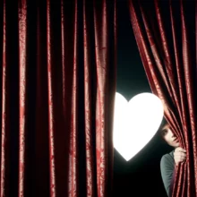 A-cute-3D-illustration-of-a-glowing-heart-symbol,-partially-hidden,-with-a-curious-person-peeking-to-discover-the-secret.