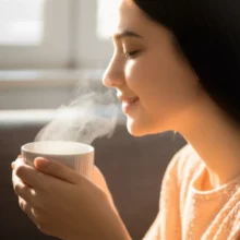 A-happy-person-feeling-refreshed,-holding-a-warm-cup-of-tea-in-the-morning-light.